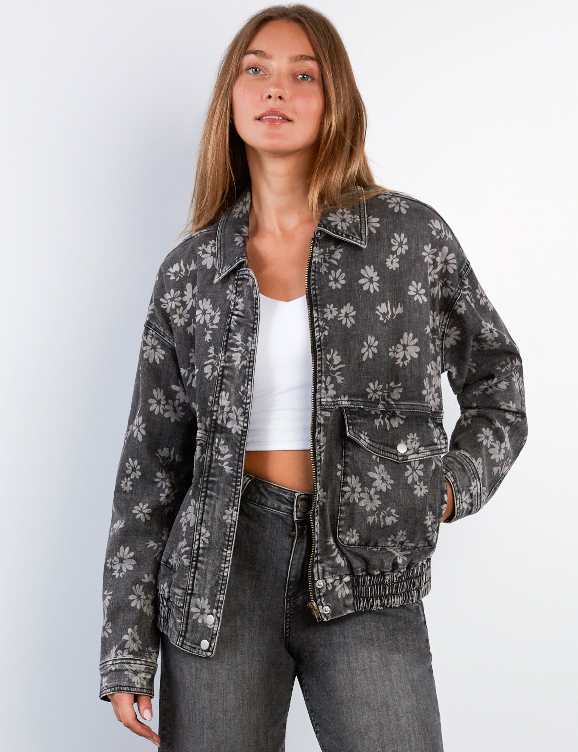 Woman wearing a floral-patterned denim jacket on a white background