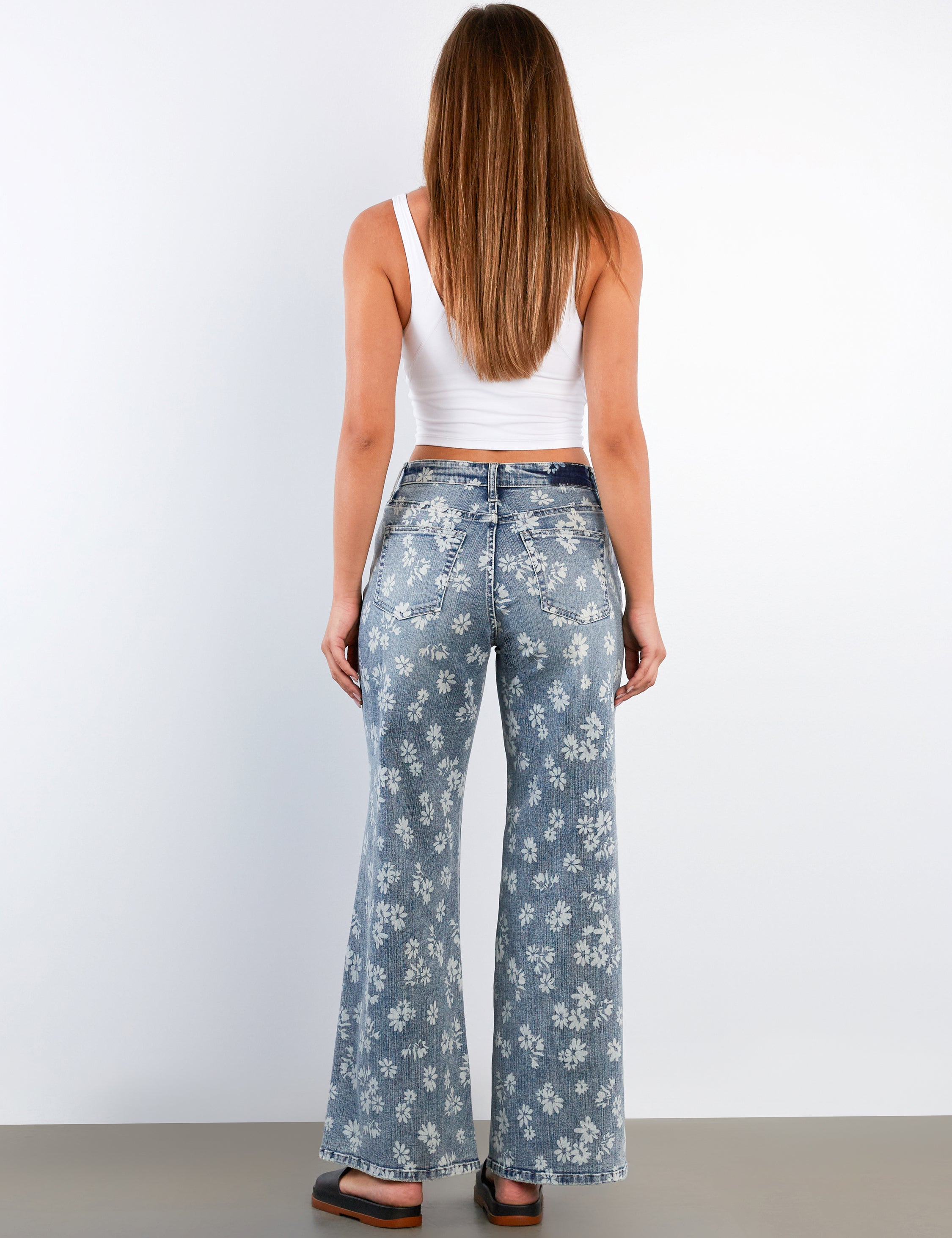 Woman wearing floral-patterned jeans on a plain background