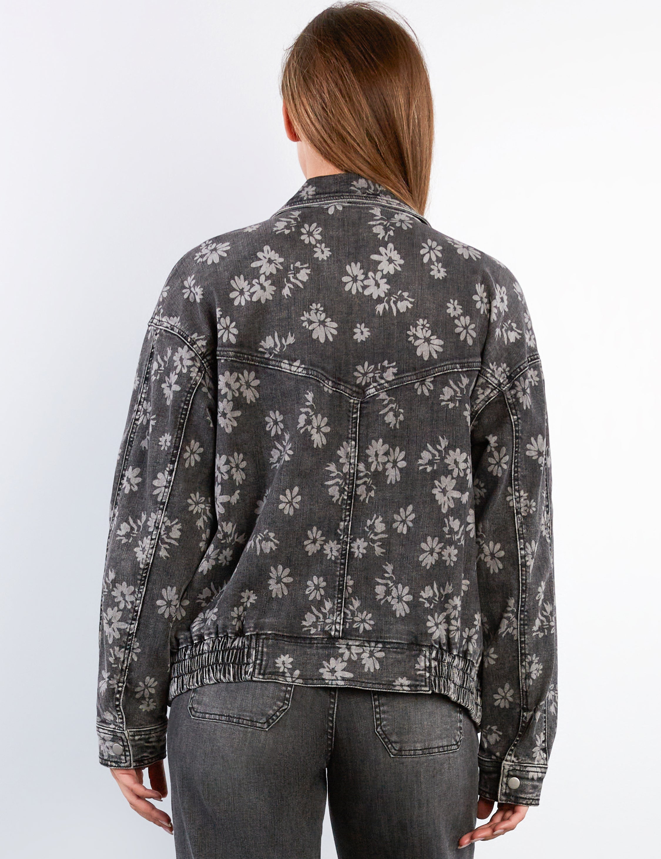 Person wearing a floral-patterned denim jacket on a white background