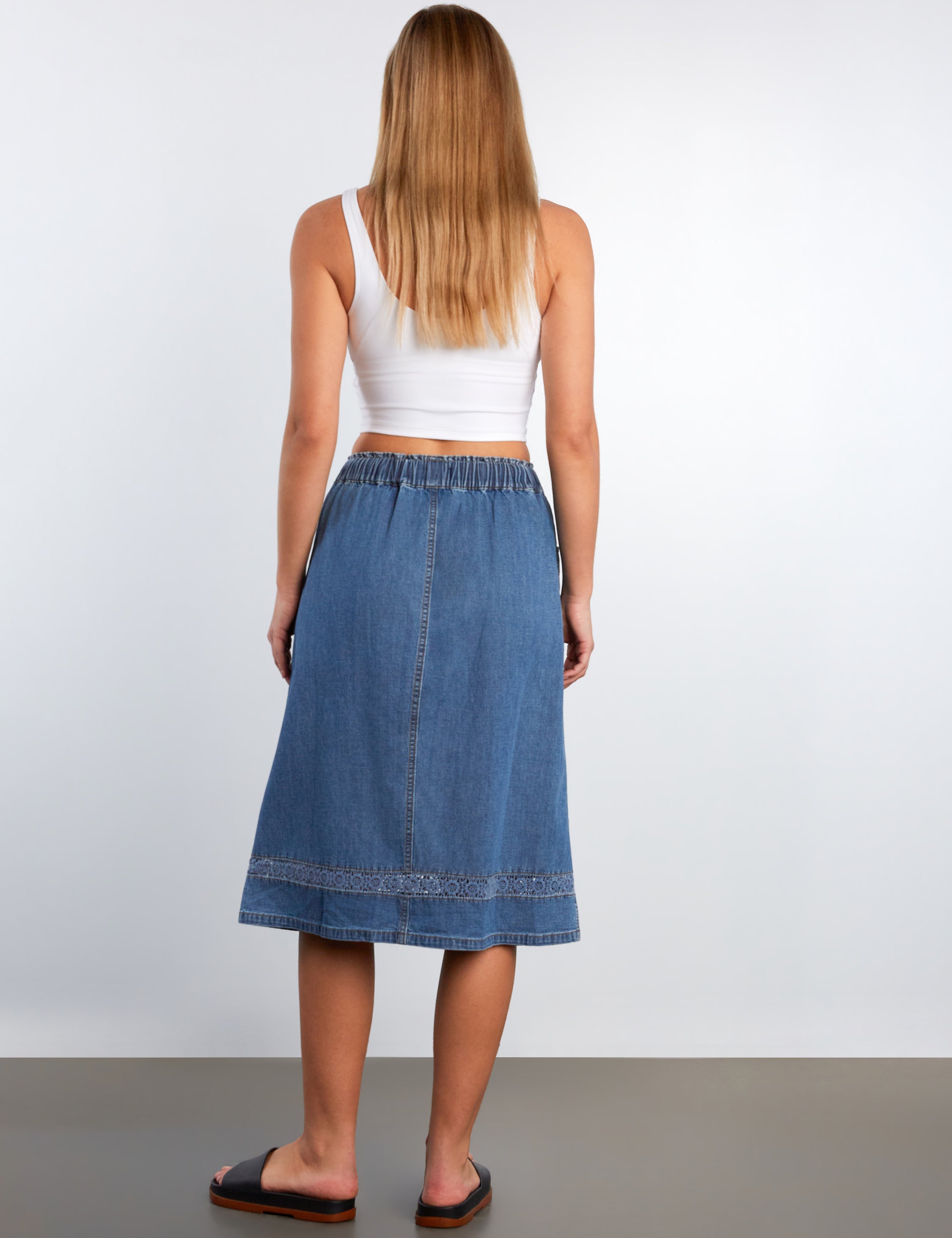 Woman wearing a blue denim skirt on a plain background