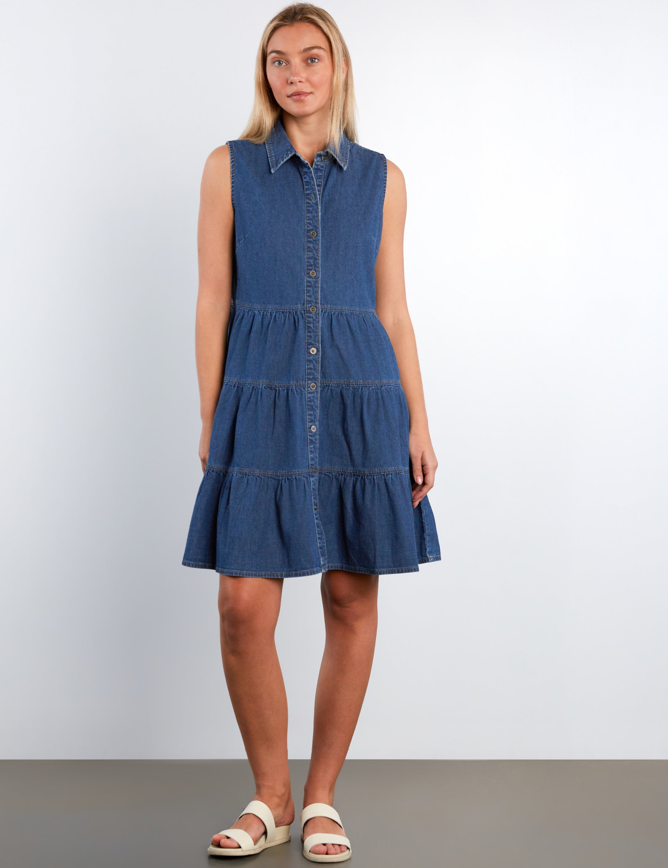 Woman wearing a blue denim dress against a white background
