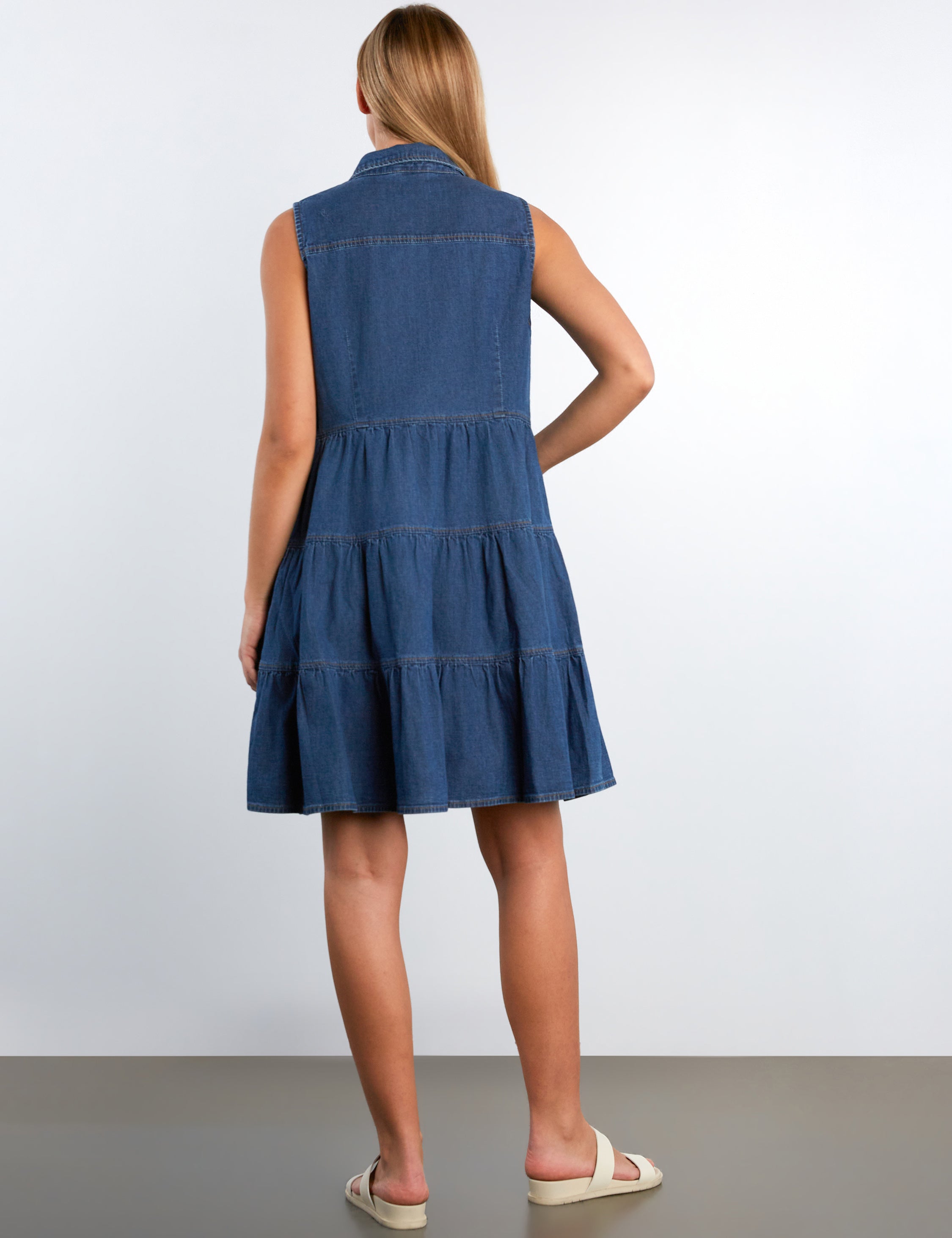 Woman wearing a blue denim dress against a white background