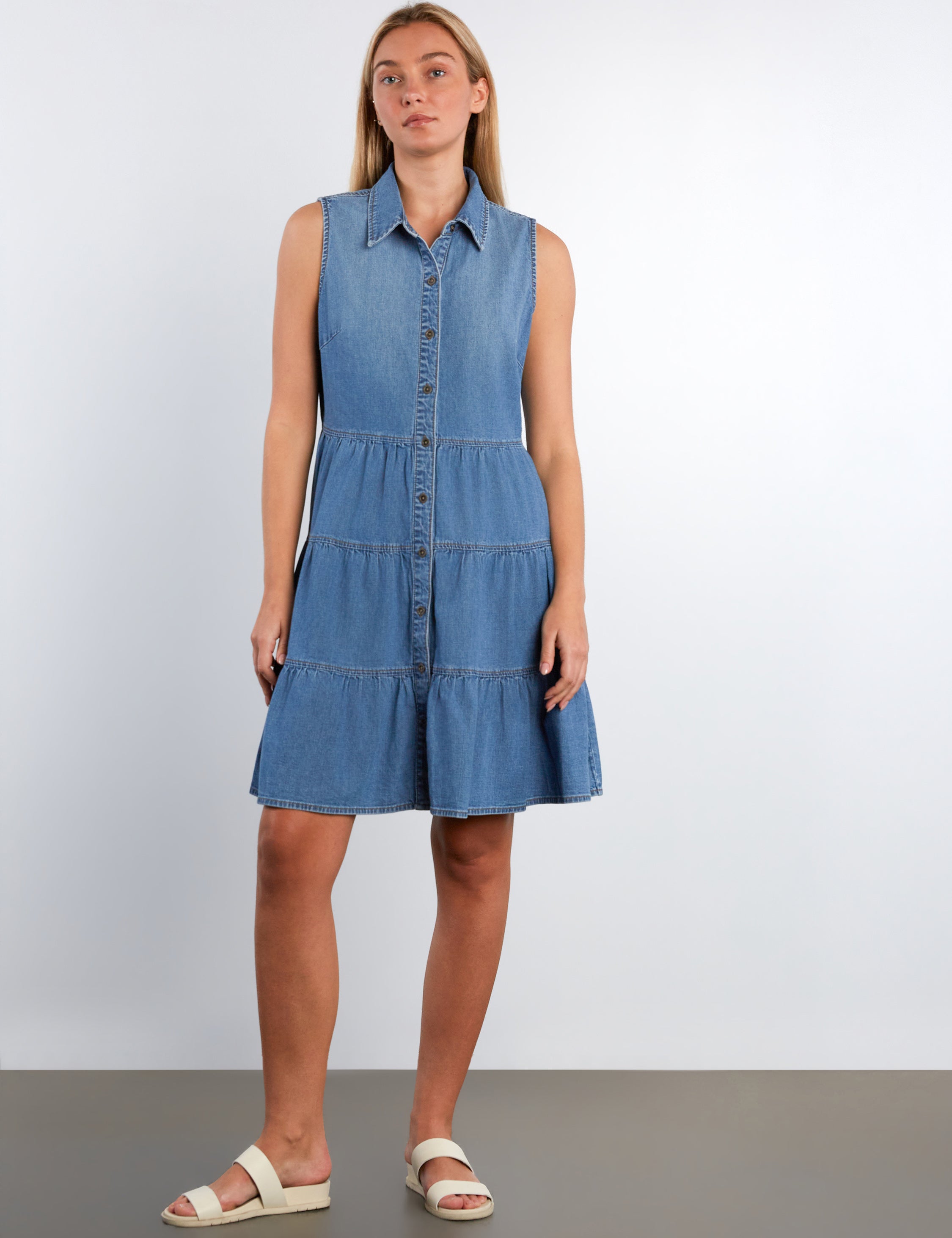 Woman wearing a blue denim dress against a white background