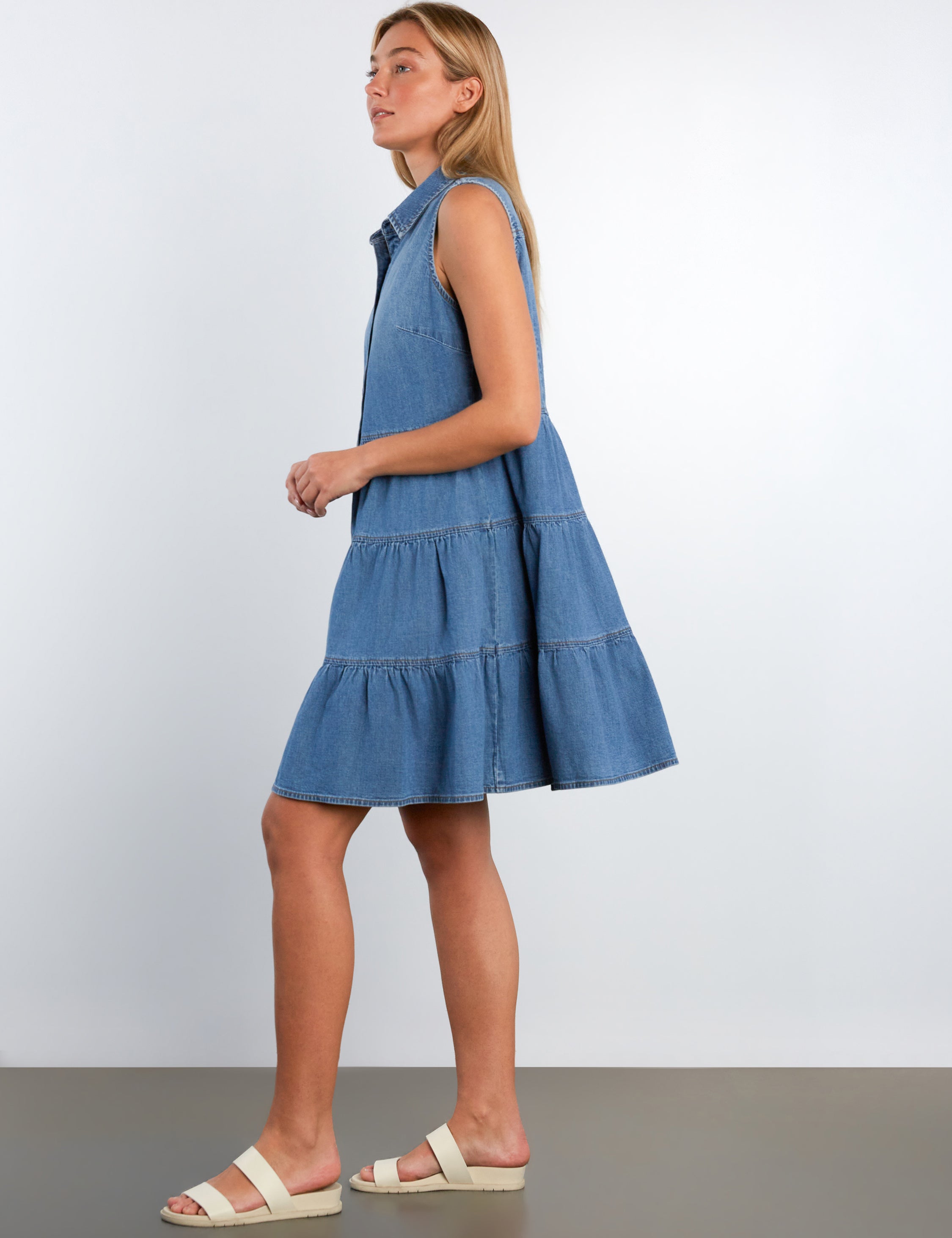 Woman wearing a blue denim dress against a white background