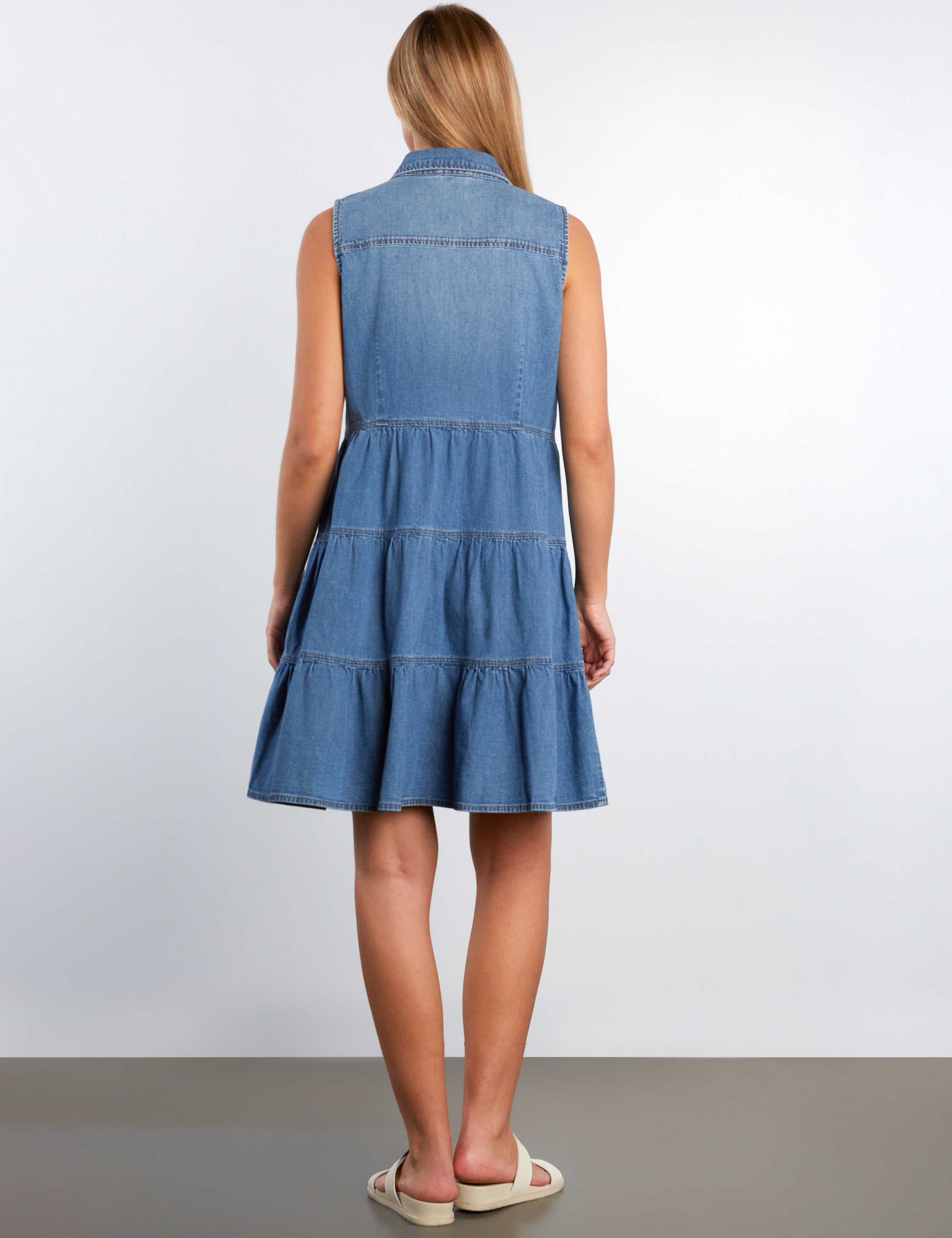 Woman wearing a blue denim dress against a white background